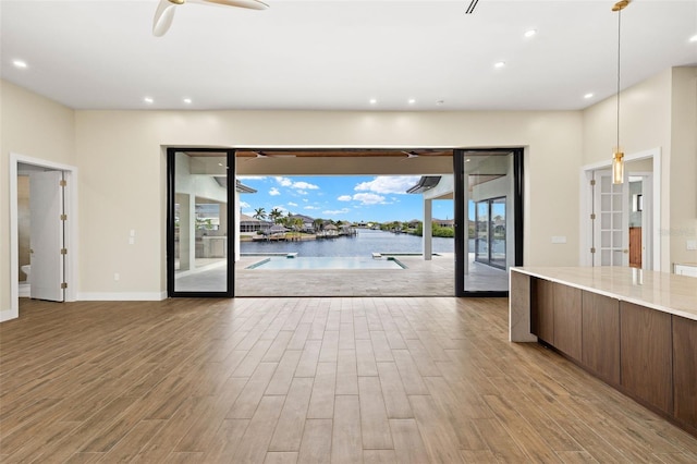 3413 NW 9th Ter, Cape Coral, FL 33904 - unfurnished living room featuring wood finished floors, a ceiling fan, recessed lighting, baseboards, and a water view