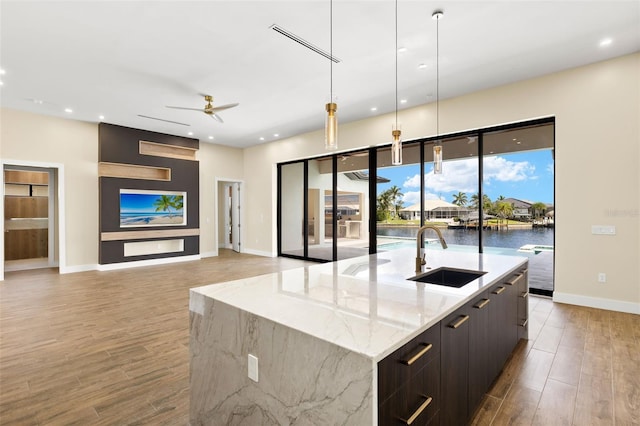 3413 NW 9th Ter, Cape Coral, FL 33904 - kitchen with a sink, modern cabinets, light wood-style flooring, a ceiling fan, and a large island