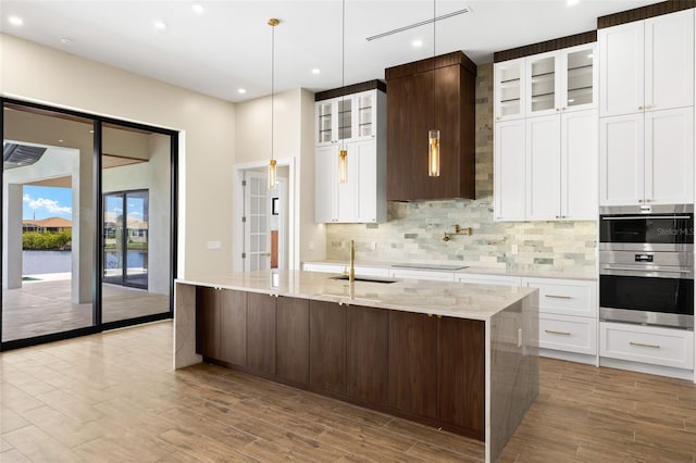 3413 NW 9th Ter, Cape Coral, FL 33904 - kitchen featuring a sink, backsplash, recessed lighting, light wood-type flooring, and a kitchen island with sink