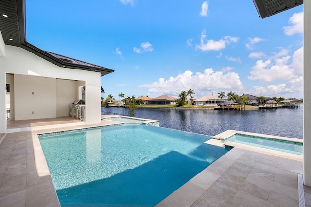 3413 NW 9th Ter, Cape Coral, FL 33904 - view of pool featuring exterior kitchen, a patio area, a water view, a pool with connected hot tub, and a residential view