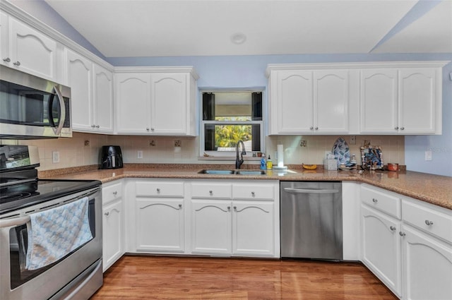 566 Reading St NW, Port Charlotte, FL 33952 - kitchen with appliances with stainless steel finishes, a sink, white cabinetry, backsplash, and lofted ceiling