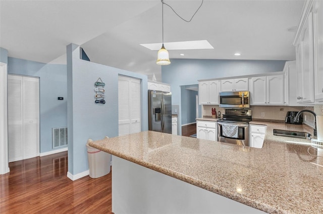 566 Reading St NW, Port Charlotte, FL 33952 - kitchen with stainless steel appliances, a sink, a skylight, a peninsula, and vaulted ceiling