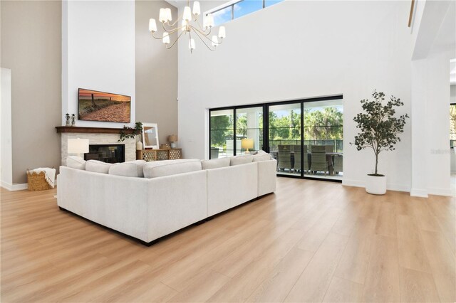 3632 Golden Gate Blvd W, Naples, FL 34102 - living area with a high ceiling, light wood-style floors, a chandelier, baseboards, and a glass covered fireplace
