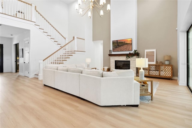 3632 Golden Gate Blvd W, Naples, FL 34102 - living room featuring a towering ceiling, light wood-type flooring, a stone fireplace, stairway, and a chandelier