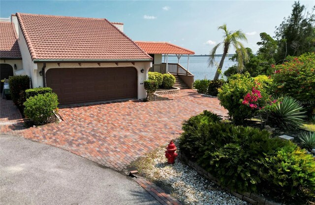 25188 Marion Ave Unit 1, Punta Gorda, FL 33950 - mediterranean / spanish home featuring a garage, stucco siding, a tiled roof, decorative driveway, and a water view