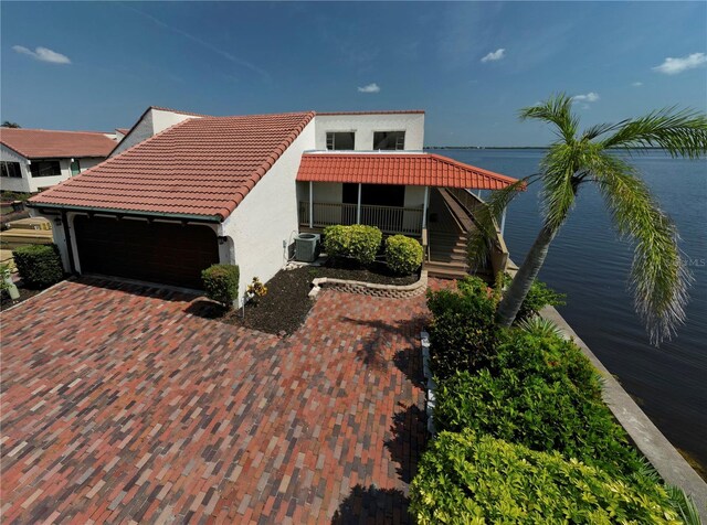 25188 Marion Ave Unit 1, Punta Gorda, FL 33950 - view of front of home featuring stucco siding, a tiled roof, central air condition unit, an attached garage, and a water view