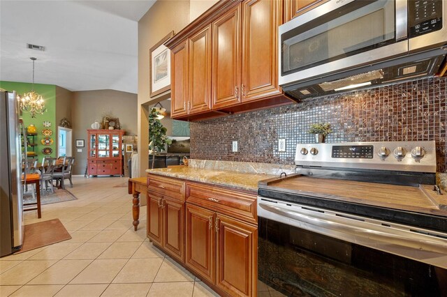 5600 Blackjack Ct S, Punta Gorda, FL 33982 - kitchen with appliances with stainless steel finishes, a chandelier, brown cabinetry, decorative backsplash, and vaulted ceiling