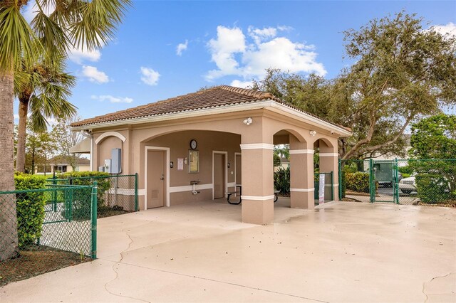 2747 Suncoast Lakes Blvd, Punta Gorda, FL 33980 - back of house with a gate, stucco siding, driveway, a carport, and a tile roof