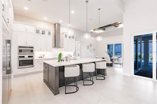 5061 Collingswood Blvd, Port Charlotte, FL 33948 - kitchen featuring wall chimney exhaust hood, a kitchen bar, double oven, light countertops, and a kitchen island with sink