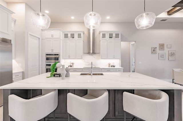 5061 Collingswood Blvd, Port Charlotte, FL 33948 - kitchen featuring wall chimney exhaust hood, a kitchen island with sink, stainless steel appliances, a sink, and white cabinets