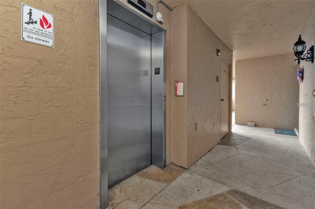 601 Shreve St Unit 64C, Punta Gorda, FL 33950 - hall with a textured wall, elevator, and a textured ceiling
