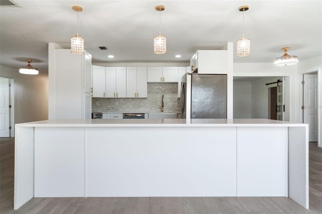 1231 Beacon Dr, Port Charlotte, FL 33952 - kitchen with stainless steel appliances, light countertops, backsplash, wood finished floors, and white cabinetry