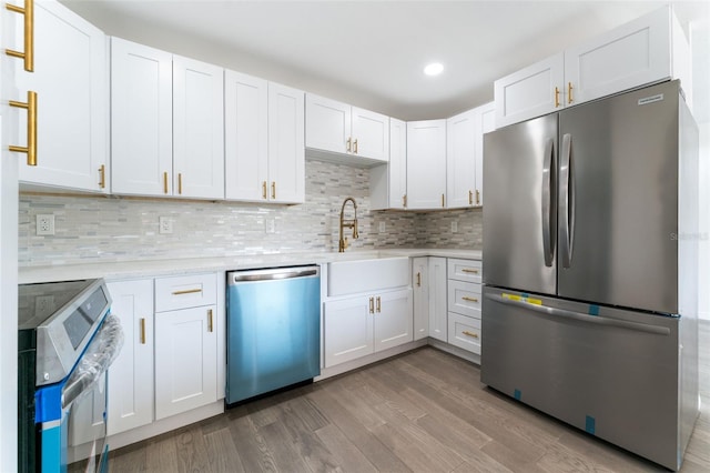 1231 Beacon Dr, Port Charlotte, FL 33952 - kitchen featuring appliances with stainless steel finishes, light countertops, a sink, wood finished floors, and backsplash