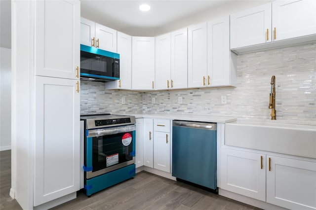 1231 Beacon Dr, Port Charlotte, FL 33952 - kitchen with stainless steel appliances, a sink, light countertops, dark wood-type flooring, and white cabinetry