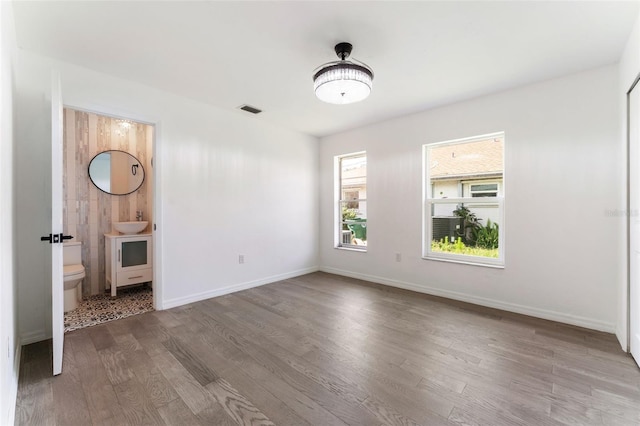 1231 Beacon Dr, Port Charlotte, FL 33952 - unfurnished bedroom featuring wood finished floors, ensuite bathroom, a sink, and baseboards
