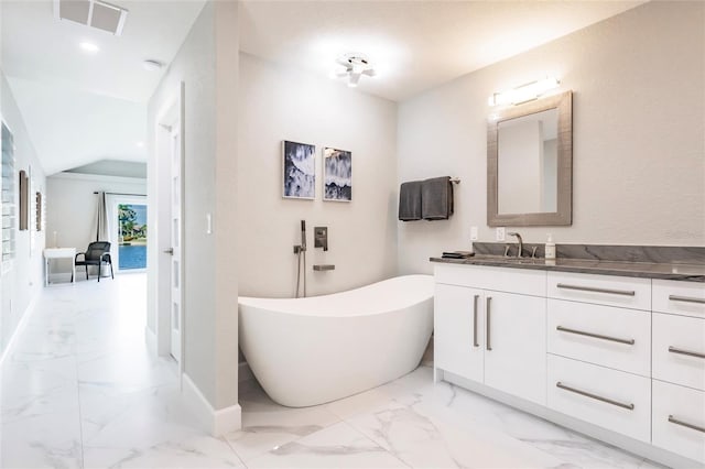 261 Venezia Ct, Punta Gorda, FL 33950 - bathroom with vanity, marble look tile flooring, a freestanding tub, baseboards, and vaulted ceiling