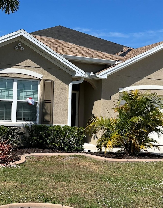 25008 Lalique Pl, Punta Gorda, FL 33950 - view of property exterior featuring stucco siding, a shingled roof, and a yard