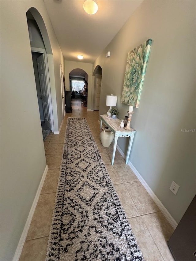 25008 Lalique Pl, Punta Gorda, FL 33950 - corridor featuring arched walkways, light tile patterned flooring, and baseboards