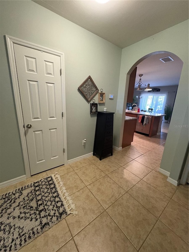 25008 Lalique Pl, Punta Gorda, FL 33950 - corridor featuring light tile patterned flooring, arched walkways, and baseboards