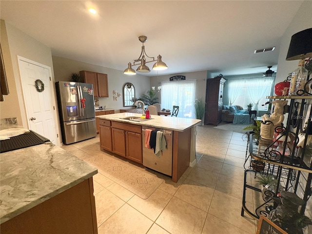 25008 Lalique Pl, Punta Gorda, FL 33950 - kitchen featuring appliances with stainless steel finishes, a sink, light tile patterned flooring, brown cabinets, and open floor plan