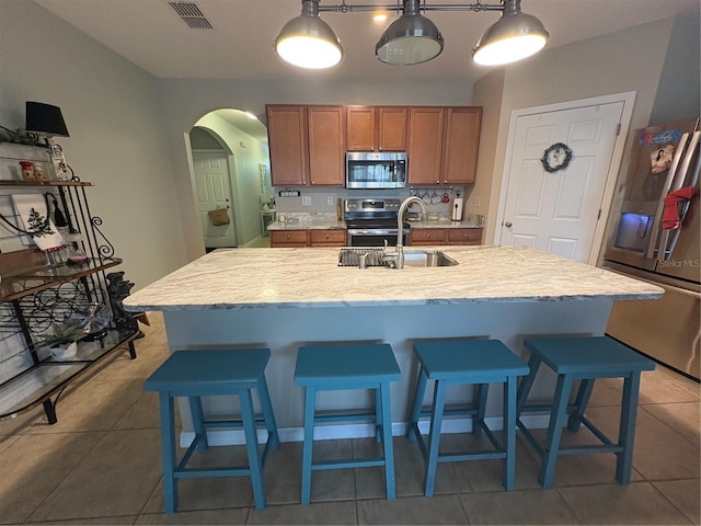 25008 Lalique Pl, Punta Gorda, FL 33950 - kitchen featuring stainless steel appliances, brown cabinets, a sink, and a breakfast bar area