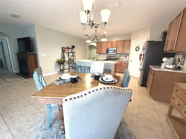 25008 Lalique Pl, Punta Gorda, FL 33950 - dining area featuring arched walkways, a chandelier, light tile patterned floors, and baseboards