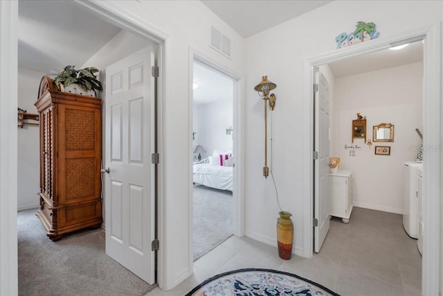 7652 Mikasa Dr, Punta Gorda, FL 33950 - hallway featuring washer and dryer, baseboards, light tile patterned floors, and light colored carpet