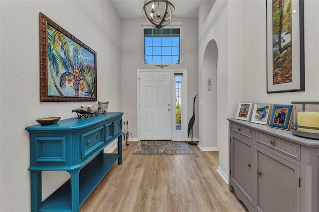 24358 Folkstone Ave, Punta Gorda, FL 33980 - foyer entrance featuring arched walkways, a chandelier, light wood-type flooring, and baseboards