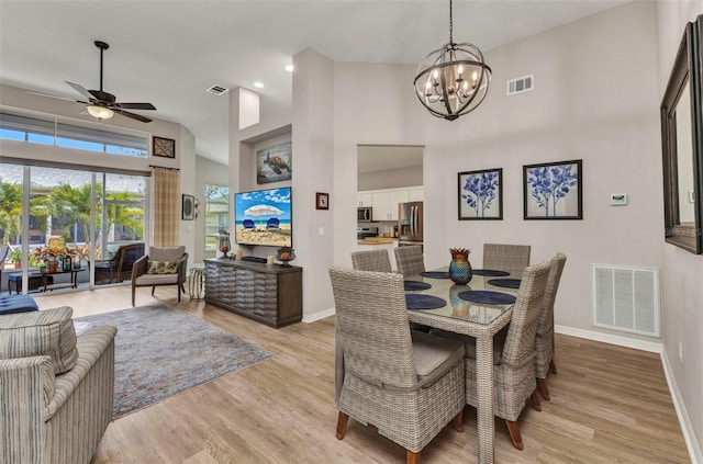 24358 Folkstone Ave, Punta Gorda, FL 33980 - dining area with a chandelier, baseboards, a ceiling fan, light wood-style floors, and a towering ceiling