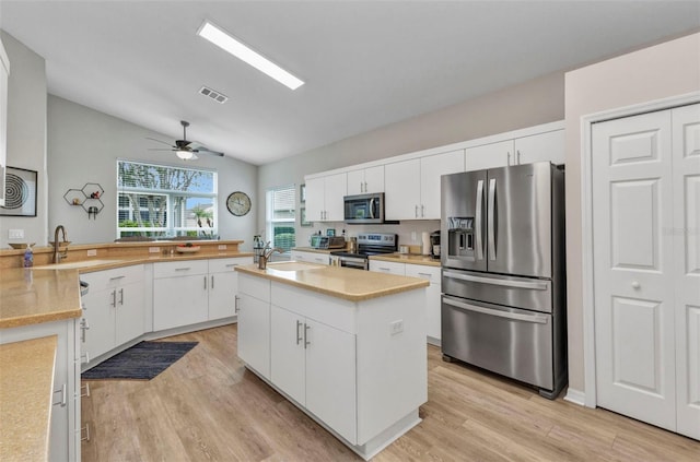 24358 Folkstone Ave, Punta Gorda, FL 33980 - kitchen featuring stainless steel appliances, vaulted ceiling, light wood-style floors, a sink, and light countertops