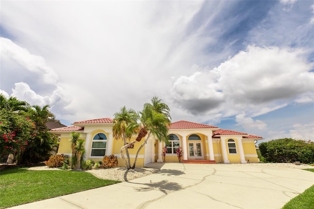 3506 Saint Florent Ct, Punta Gorda, FL 33950 - mediterranean / spanish-style house with french doors, concrete driveway, a tiled roof, stucco siding, and a front lawn