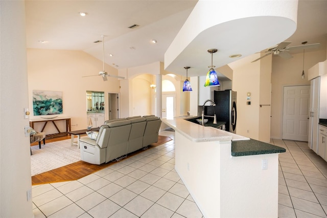 3506 Saint Florent Ct, Punta Gorda, FL 33950 - kitchen with a ceiling fan, stainless steel fridge, arched walkways, light tile patterned floors, and high vaulted ceiling
