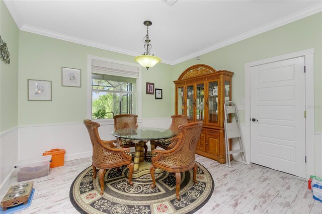 13204 Kakapo Ave, Port Charlotte, FL 33981 - dining room with light wood-style flooring, ornamental molding, and a wainscoted wall