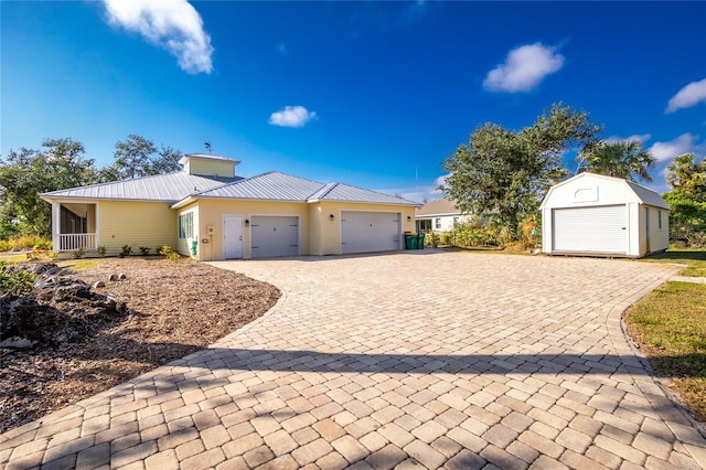 13204 Kakapo Ave, Port Charlotte, FL 33981 - view of front of house featuring an attached garage, decorative driveway, metal roof, and an outbuilding