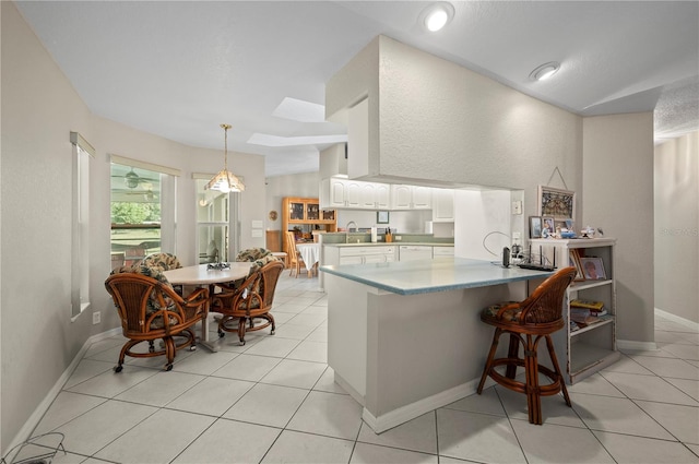 891 Bayard St, Port Charlotte, FL 33948 - kitchen with a peninsula, white cabinets, pendant lighting, light tile patterned flooring, and a breakfast bar