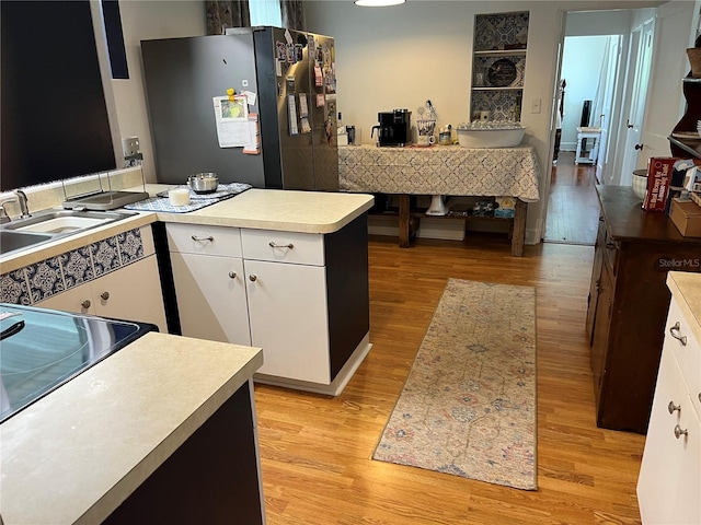 404 W Whidden St, Arcadia, FL 34266 - kitchen with stainless steel fridge, light wood-style flooring, white cabinets, light countertops, and a sink