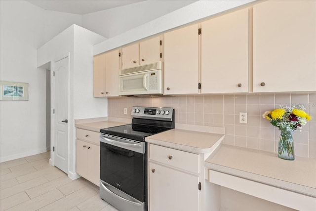 7334 N Tulip Tree, Punta Gorda, FL 33955 - kitchen featuring stainless steel electric stove, white microwave, light countertops, and backsplash