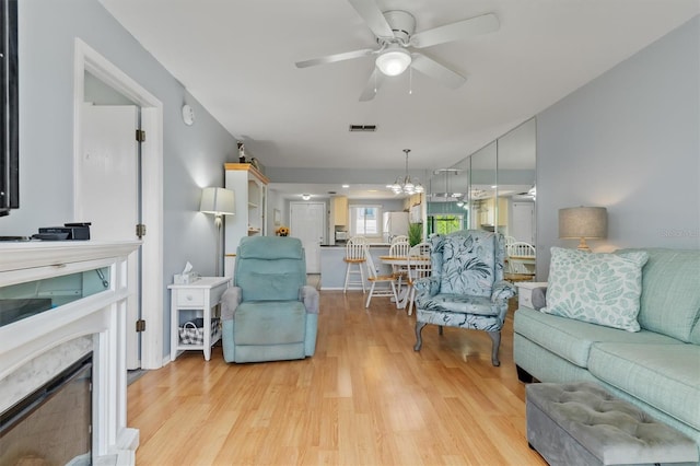 25275 Rampart Blvd Unit 1504, Punta Gorda, FL 33983 - living area with ceiling fan, light wood-style flooring, a chandelier, and a fireplace