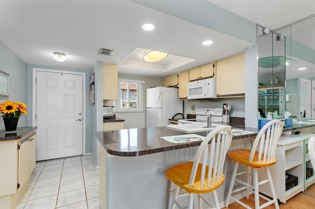 25275 Rampart Blvd Unit 1504, Punta Gorda, FL 33983 - kitchen with white appliances, a peninsula, dark countertops, cream cabinetry, and recessed lighting