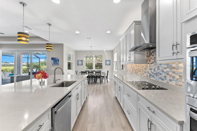 19821 Montenero Way, Venice, FL 34293 - kitchen with a sink, appliances with stainless steel finishes, wall chimney exhaust hood, light wood-style floors, and recessed lighting