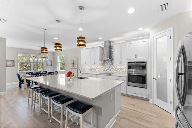 19821 Montenero Way, Venice, FL 34293 - kitchen featuring wall chimney exhaust hood, stainless steel appliances, a sink, a breakfast bar area, and tasteful backsplash