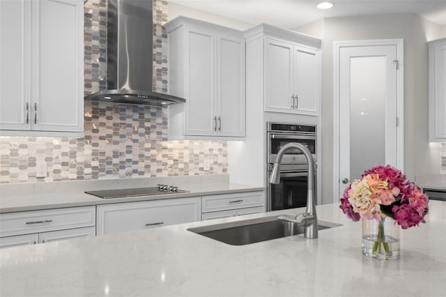 19821 Montenero Way, Venice, FL 34293 - kitchen featuring wall chimney exhaust hood, a sink, double oven, black electric stovetop, and tasteful backsplash