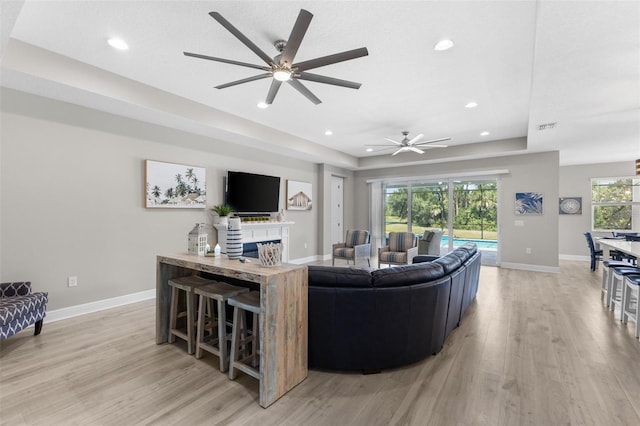 19821 Montenero Way, Venice, FL 34293 - living area with light wood-style flooring, recessed lighting, baseboards, a ceiling fan, and a tray ceiling
