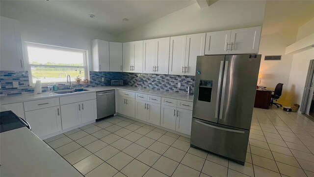 24239 Yacht Club Blvd, Punta Gorda, FL 33955 - kitchen with stainless steel appliances, light tile patterned flooring, light countertops, tasteful backsplash, and vaulted ceiling