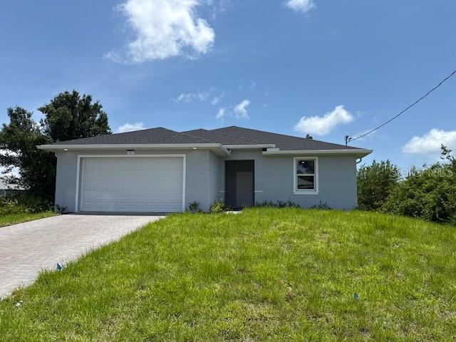 207 Baytree Dr, Rotonda West, FL 33947 - view of front facade with a garage, stucco siding, driveway, and a front yard