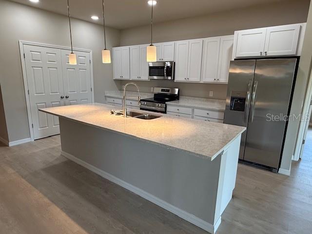207 Baytree Dr, Rotonda West, FL 33947 - kitchen featuring appliances with stainless steel finishes, a sink, light wood-type flooring, recessed lighting, and white cabinets