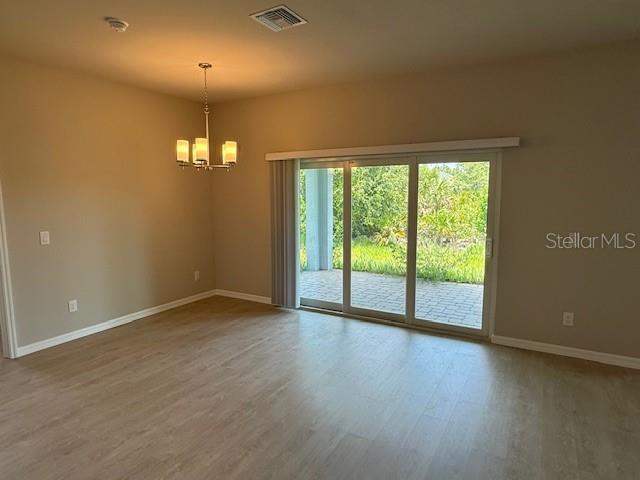 207 Baytree Dr, Rotonda West, FL 33947 - empty room featuring a chandelier, baseboards, and wood finished floors