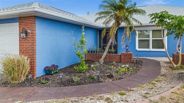 10229 Gulfstream Blvd, Englewood, FL 34224 - view of side of home with a garage, stucco siding, and roof with shingles
