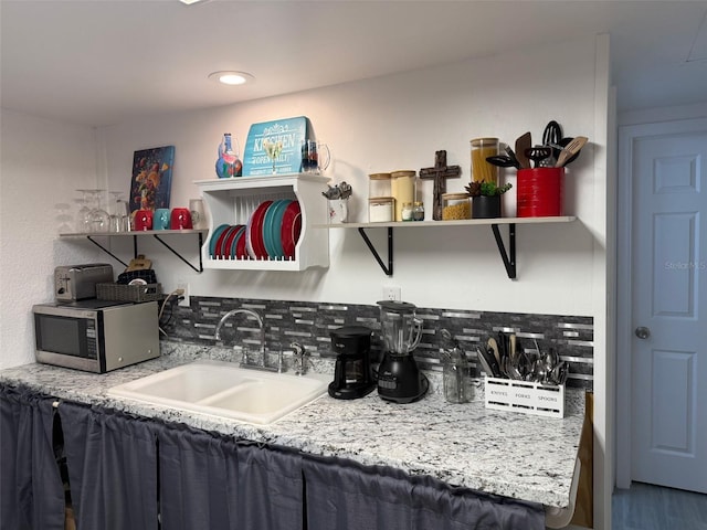 5727 Beechwood St, Punta Gorda, FL 33982 - kitchen with open shelves, stainless steel microwave, a sink, backsplash, and wood finished floors