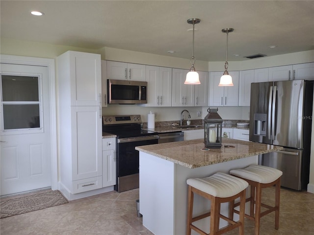 9986 SW Riverview Cir, Arcadia, FL 34269 - kitchen with appliances with stainless steel finishes, light stone counters, a kitchen breakfast bar, a kitchen island, and white cabinetry